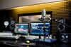 Close up of a mic with audio editing equipment in the background